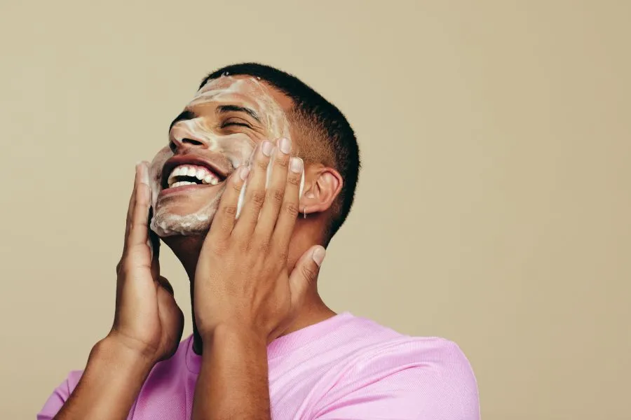 A man washing his face while smiling.